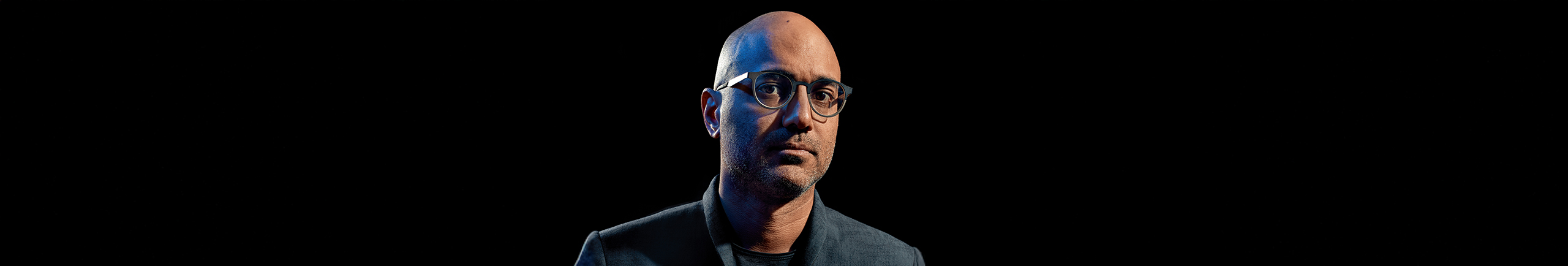 Image of SSSB author Ayad Akhtar. Man with glasses on a black backdrop.